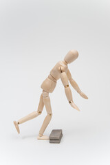 右向きに歩いて床の障害物につまずくデッサン人形