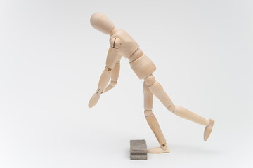 左向きに歩いて床の障害物につまずくデッサン人形