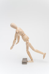 左向きに歩いて床の障害物につまずくデッサン人形