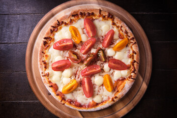 Pizza with mozzarella cheese and cherry tomatoes on wooden background. Soft focus. Top view. Close up.