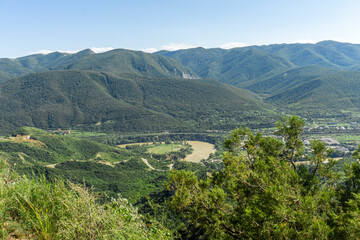 Obraz premium Valley and river Mtkvari (Kura), view from above from the hill. Green meadows, mountains, blue sky, village houses.
