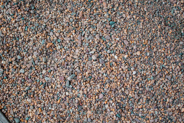 Stony beach on a sunny day. Background of different pebbles from above on the beach