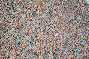 Stony beach on a sunny day. Background of different pebbles from above on the beach