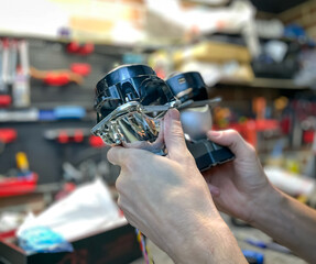 Installation of BI-LED lenses in the headlight. Restoration of car optics. A man holds a bi-led...