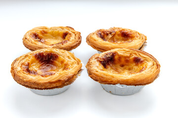 Four baked egg tarts isolated on white.