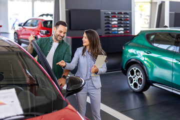 Young woman consultant in show room talking with client, Professional salesperson selling cars at...