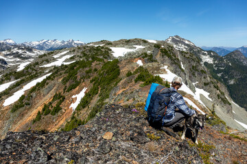 A man pets his dog on an adventure high alpine of the mountains