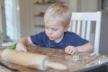 Young boy focused on baking cookies with dough and cookie cutter