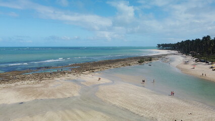 Vue aérienne panoramique d’une plage en bord de mer avec eau turquoise et bateau
