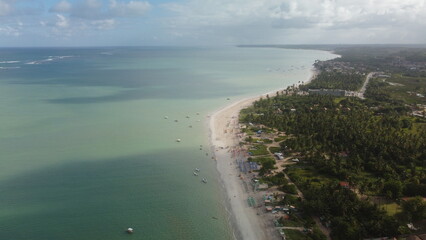 Vue aérienne panoramique d’une plage en bord de mer avec eau turquoise et bateau
