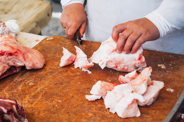 the hands of a butcher cutting lard meat.