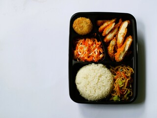 Katsu chicken, rice, noodles, mashed potatoes, vegetable salad, and fritter served on bento box meal isolated white, copy space. Suitable for students and busy worker, home business opprtunity