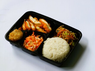 Katsu chicken, rice, noodles, mashed potatoes, vegetable salad, and fritter served on bento box meal isolated white, copy space. Suitable for students and busy worker, home business opprtunity