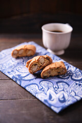 Cantuccini (Italian cookies) and a cup of coffee on dark wooden background. Close up..