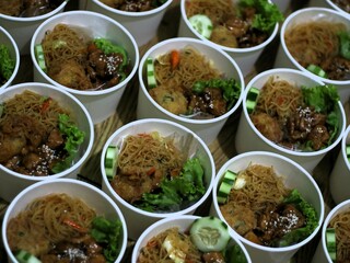 Amounts of teriyaki glazed chicken rice bowl with vegetables, noodle, sliced cucumber and wortel and mashed potatoes on black background. Balanced nutritious food