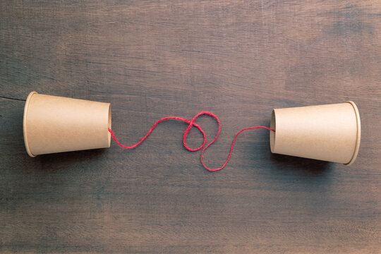 Brown cups phone with red string set on old wooden board, old style phone, two-way communication