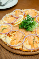 Fresh salmon pizza topped with shallot slices and lettuce, served in the restaurant