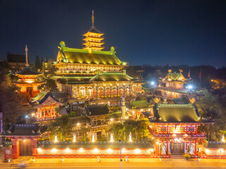 Aerial night view of Minh Thanh pagoda, a majestic Buddhist architectural structure in Pleiku city, Gia Lai province, Vietnam, text in photo mean Peace, Happy New Year.