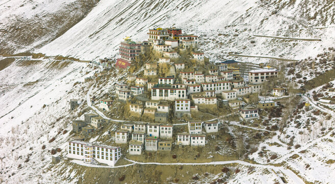 Key Gompa glowing under the golden hues of sunset, its whitewashed walls contrasting beautifully with the deep shadows cast by towering mountains.