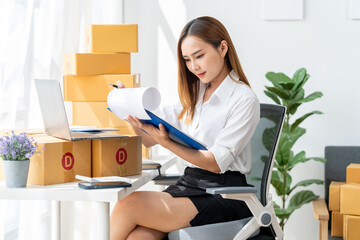 Entrepreneurial Spirit:  A focused young woman manages her online business, meticulously reviewing...