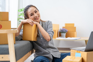 Smiling Entrepreneur:  A young, Asian businesswoman smiles confidently amidst a sea of neatly stacked cardboard boxes, symbolizing the success and growth of her online business.