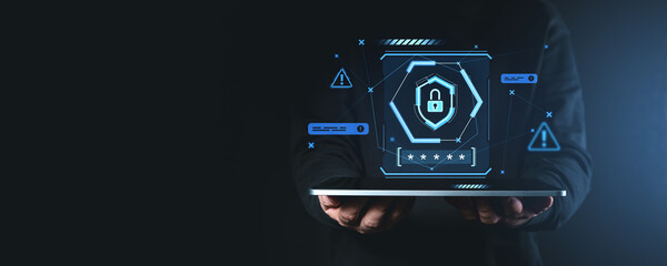 Hands holding tablet with holographic cybersecurity icons on dark background.