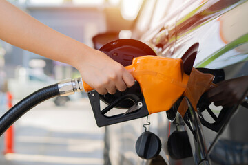 Woman driver hand refilling and pumping gasoline oil the car with fuel at he refuel station.