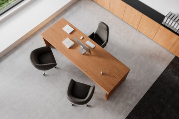 Naklejka premium Minimalist modern office setup with wooden desk and dark chairs on concrete floor. 3D Rendering