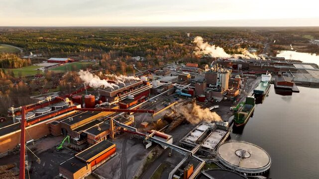 Pulp and paper mill releasing steam and smoke at sunset
