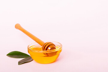 Honey in jar with leaves and honey dipper on colored background top view with copy text