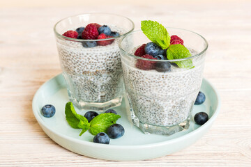 Healthy breakfast or morning with chia seeds vanilla pudding raspberry and blueberry berries on table background, vegetarian food, diet and health concept. Chia pudding with raspberry and blueberry
