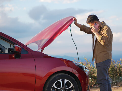 Young asian man with broken car calling auto repair shop - Powered by Adobe