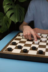 Naklejka premium game of checkers. checkers board with checkers placed on it. male hand makes a move