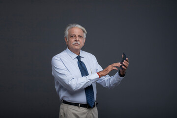 Naklejka premium Senior Old Man On A Serious Expression Holding A Calculator