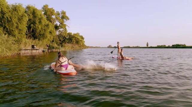 Group of friends on sup board enjoying a day at lake during sunset.