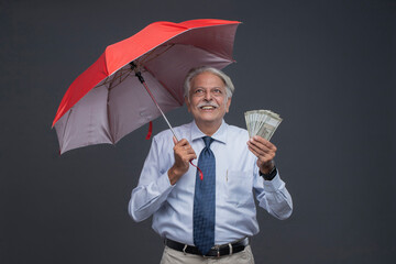Older Man Looking Up While Holding An Umbrella And Indian Notes