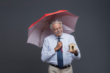 Old Age Man Watching House Toy While Holding Umbrella 