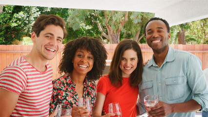 Portrait Of Group Of Smiling Young Friends Enjoying Summer Drinks Outdoors In Garden At Home