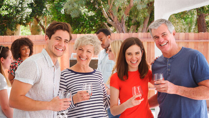Portrait Of Family With Senior Parents And Adult Offspring Outdoors At Home Enjoying Barbecue Meal