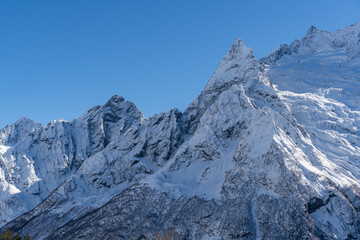 Snow-capped peaks with majestic blue slopes rise above jagged slopes of North Caucasus Range. Mountain tops are covered with eternal glaciers. Dombay. Karachay-Cherkessia.