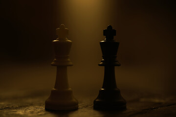 Dramatic Chess Game with Illuminated Black and White Kings in Low Light Setting