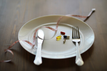 Dietary Supplements on Plate with Knife, Fork, and Measuring Tape Signifying Health and Nutrition