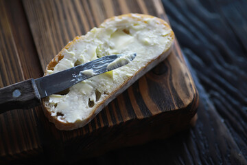 Rustic Bread Slice with Butter on Wooden Cutting Board - Close-Up