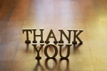 Golden THANK YOU Letters on Wooden Surface - Appreciation Gesture and Gratitude Concept