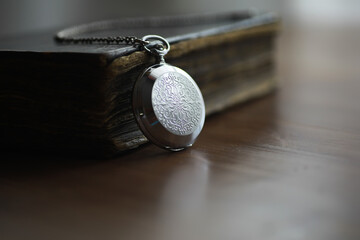 Vintage Silver Pocket Watch with Ornate Design Resting on Antique Book