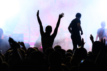 Backlit concert scene with cheering audience silhouette