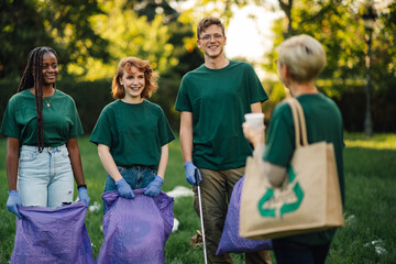 Group of volunteers collecting garbage in park are taking break