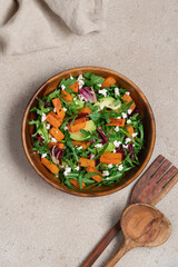 Sweet potato salad with arugula, avocado, cucumber and veta cheese in wooden bowl on light background. Healthy food top view. Food background with copy space