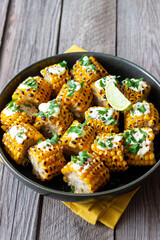 Grilled corn with white sauce and herbs. BBQ. Picnic. Vegetarian food. Diet.