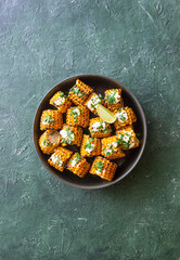 Grilled corn with white sauce and herbs. BBQ. Picnic. Vegetarian food. Diet.